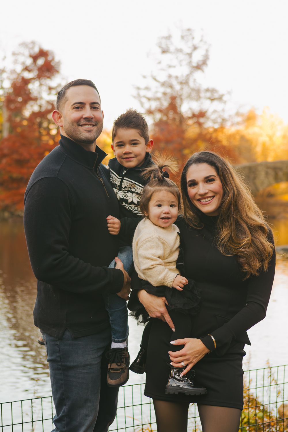 Professional family portraits in NYC with the Plaza Hotel and city skyline in the distance.