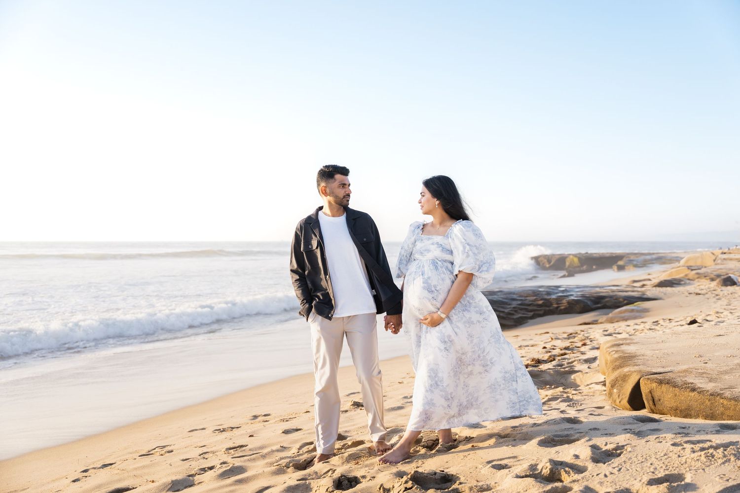 Couple holding hands for maternity session at the beach in La Jolla