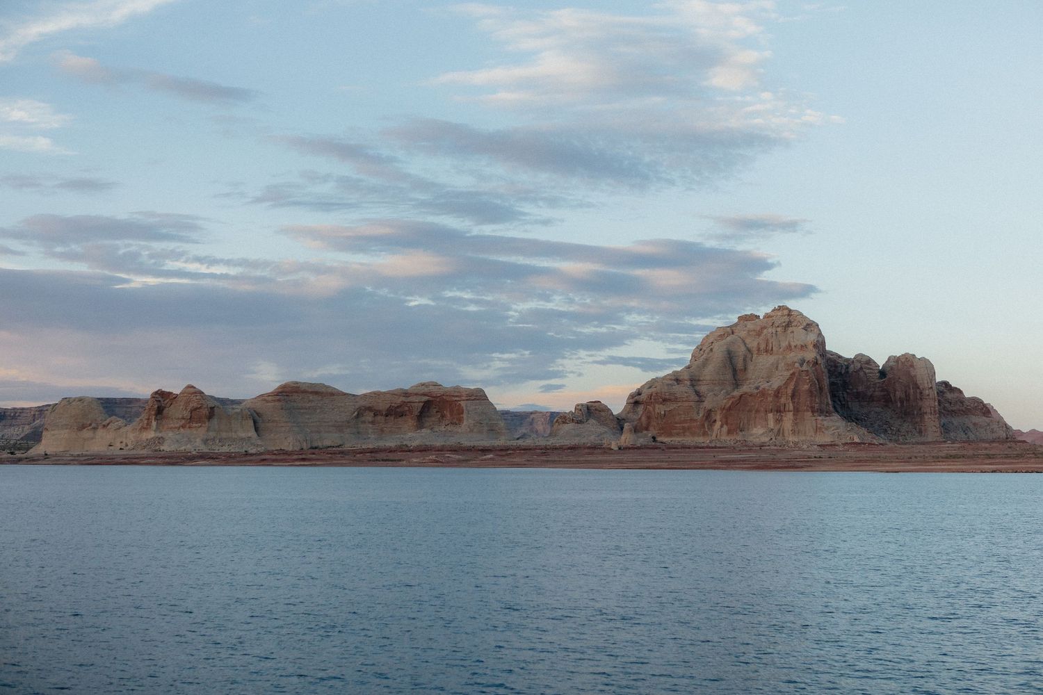 Expansive panoramic view of Lake Powell's blue waters surrounded by towering red rock cliffs and desert landscape.