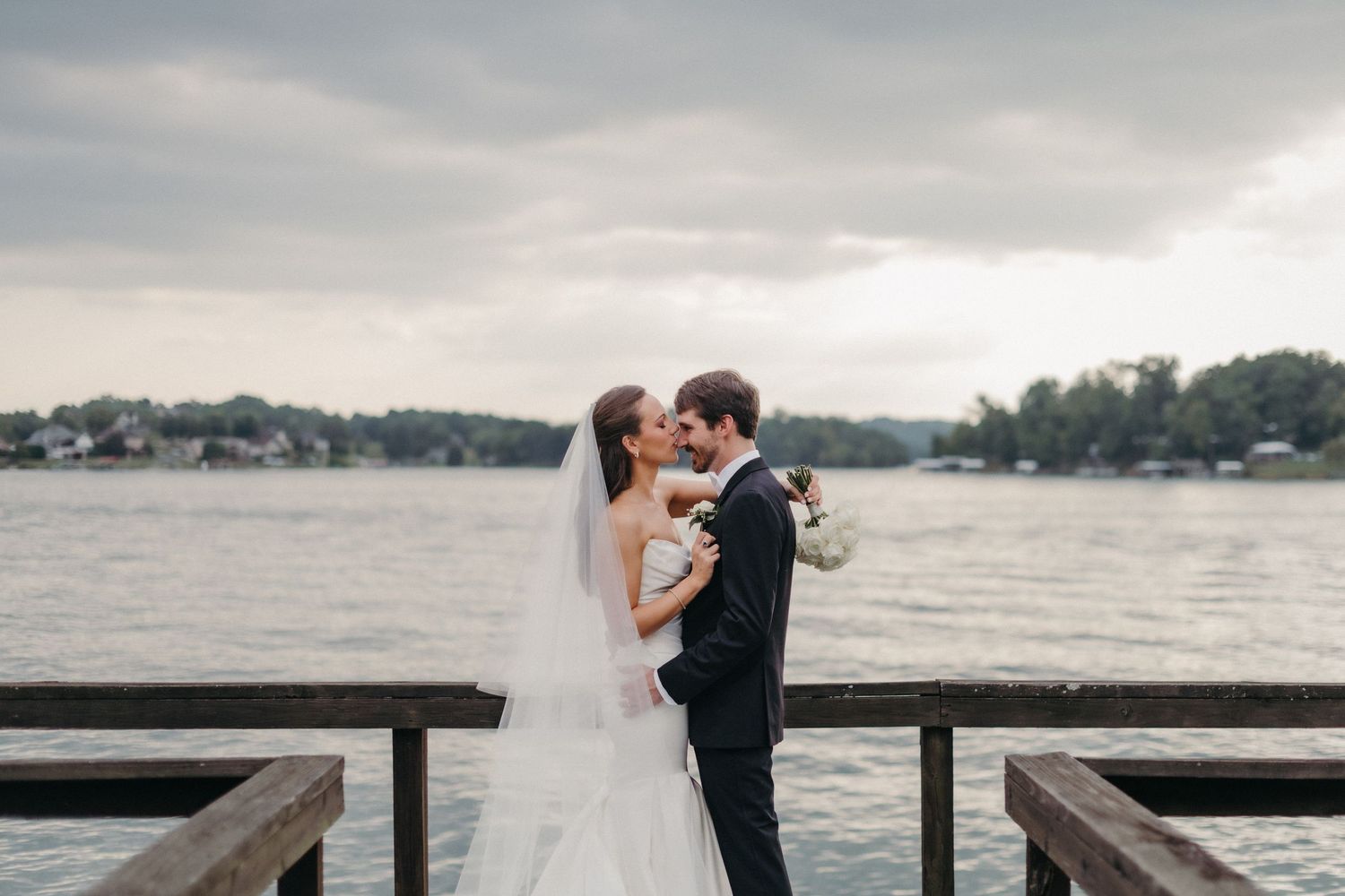 A romantic lakeside wedding celebration with scenic water views and a wooden dock at sunset.