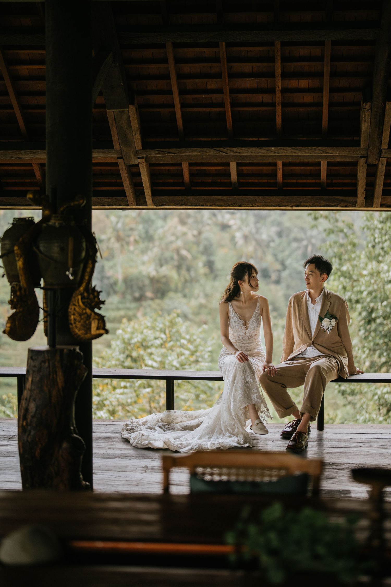 Wedding couple poses together in a garden setting with beautiful green foliage in the background.