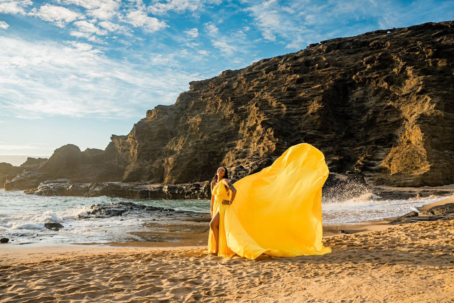 A yellow tent with ocean waves and coastal cliffs in the background during golden hour at sunset.
