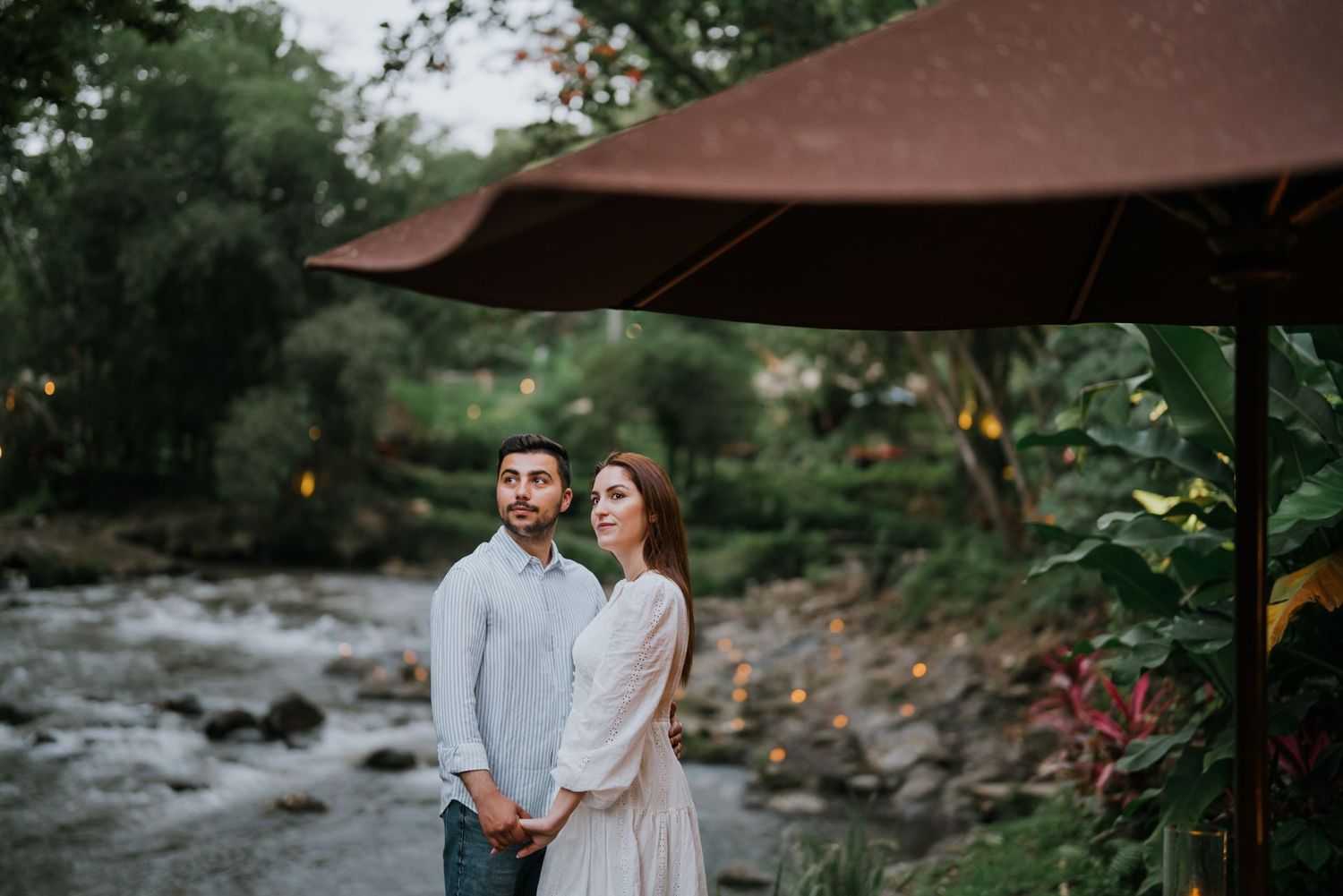 Romantic garden photoshoot with natural greenery and water features in the background.
