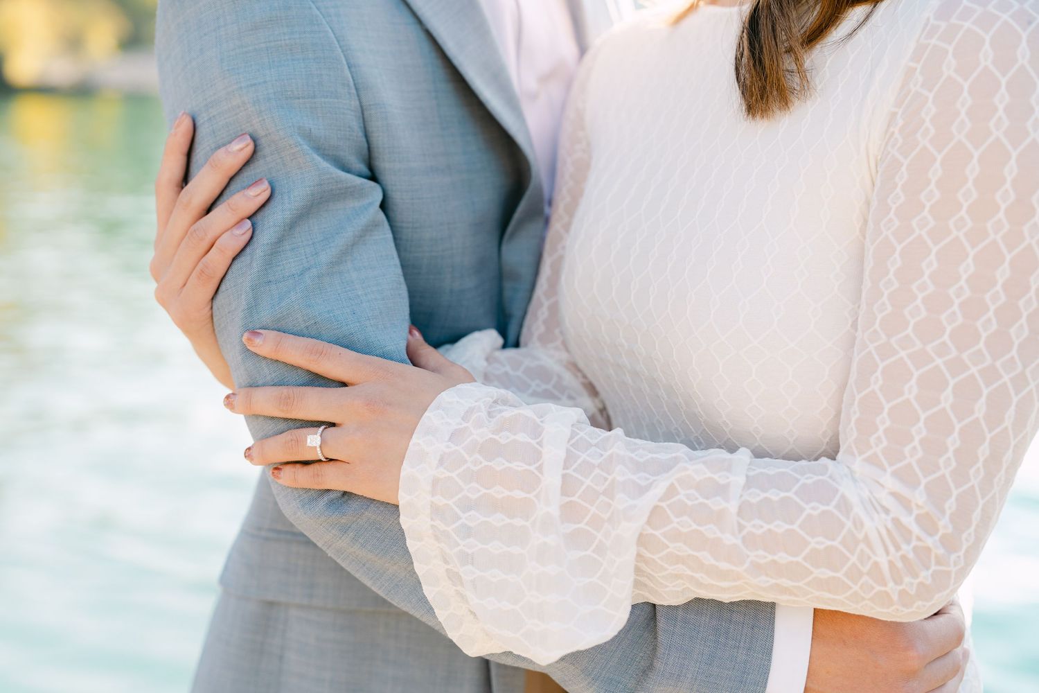 Couple holding hands in romantic pose wearing light mint dress with crystal belt and white striped shirt in Iseltwald.