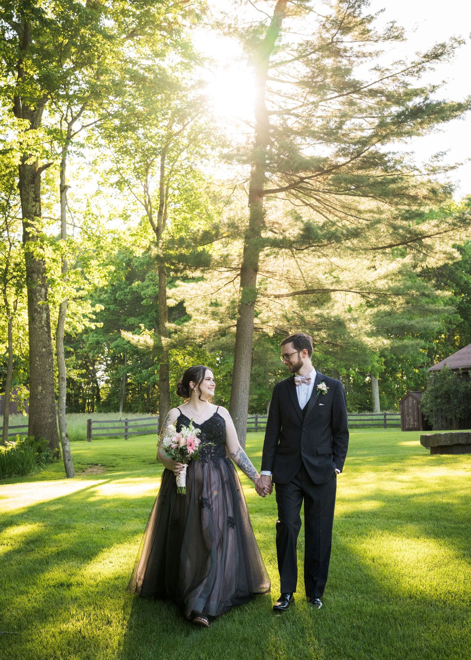 Newlyweds share an intimate moment outdoors with autumn foliage and rustic architecture in background.
