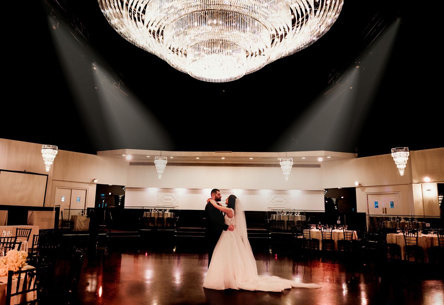 A chandelier glows from above, casting warm light across an elegant ballroom during a special event.