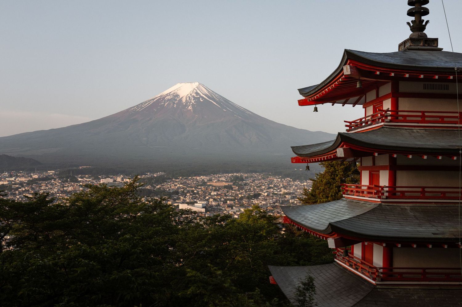 Red Japanese pagoda with Mount Fuji snow-capped peak in background at dusk, Chureito Pagoda, Fujiyoshida, Japan.