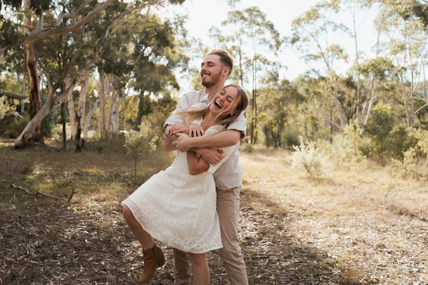 Happy couple having fun, laughing outdoors in a sunny eucalyptus forest setting in Rouse hill regional park during a photoshoot