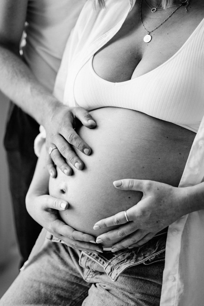 A black and white photo series showing a pregnant belly with hands resting on it in different positions.
