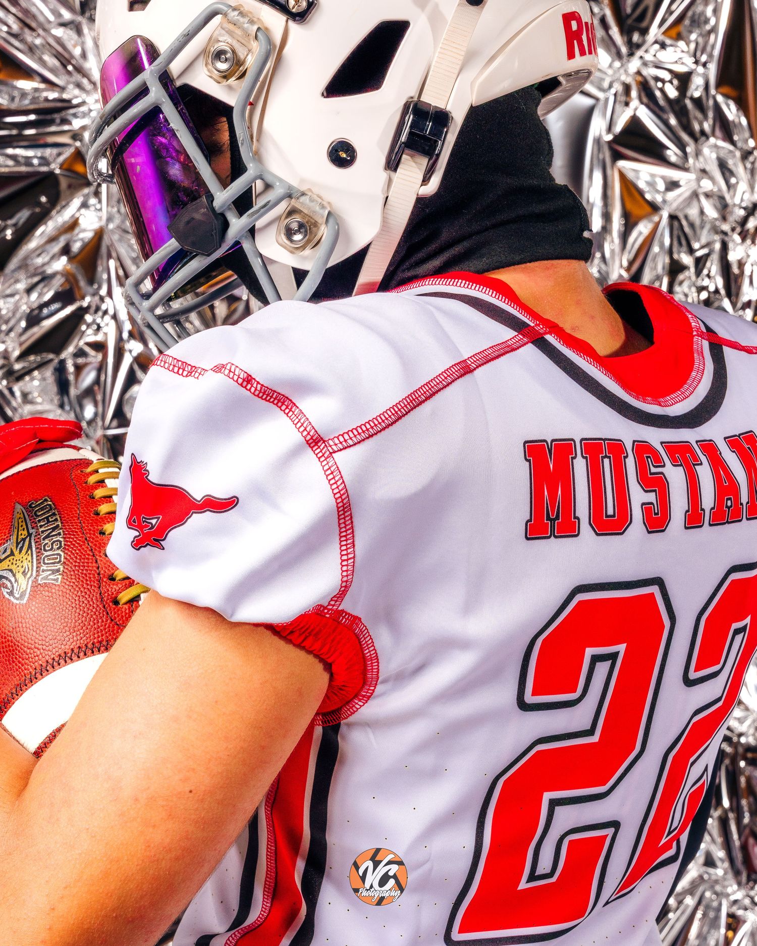 Football player in white Mustangs jersey number 22 holding ball, wearing white helmet with face mask.