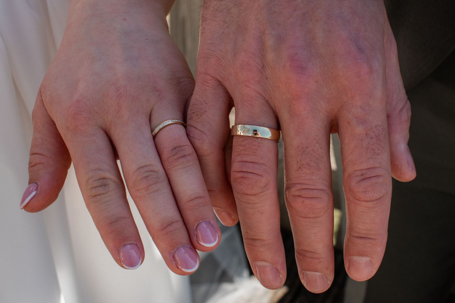 Two hands displaying silver wedding rings on ring fingers, symbolizing marriage and commitment.