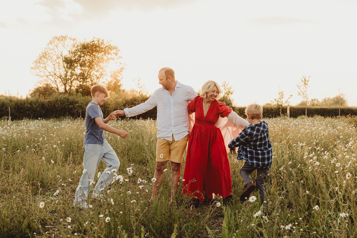 A joyful family plays together in a sunlit wildflower meadow at golden hour.