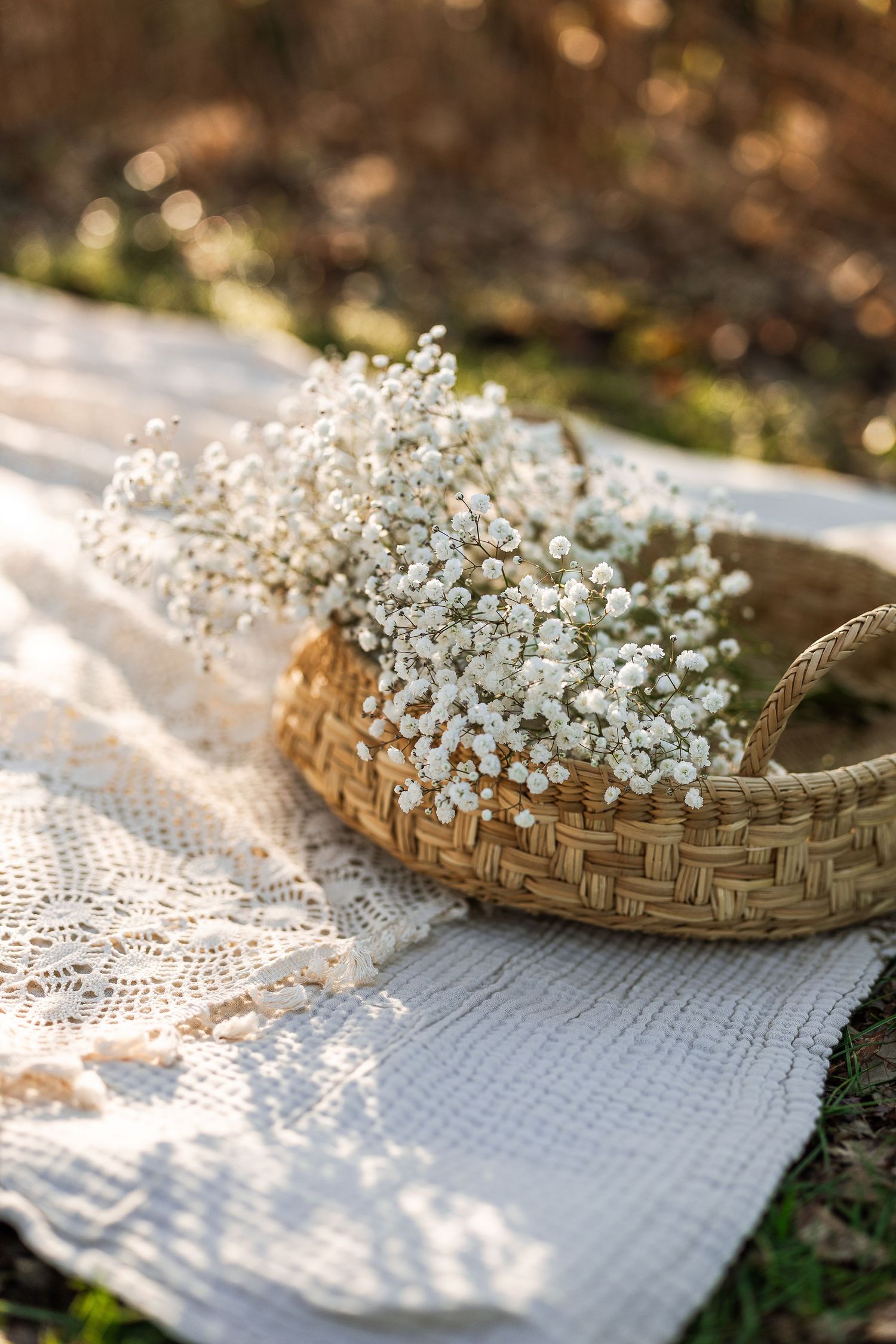 Delicate white baby's breath flowers arranged in a woven basket on a textured linen cloth in soft natural lighting.