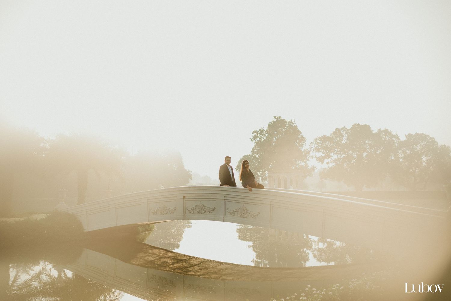 Misty morning silhouette of figures standing on reflective surface near trees.
