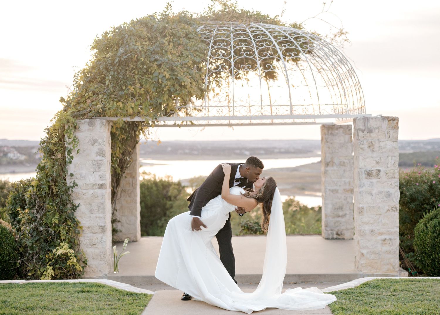 groom dipping his bride in front of ceremony gazebo in Austin, TX.