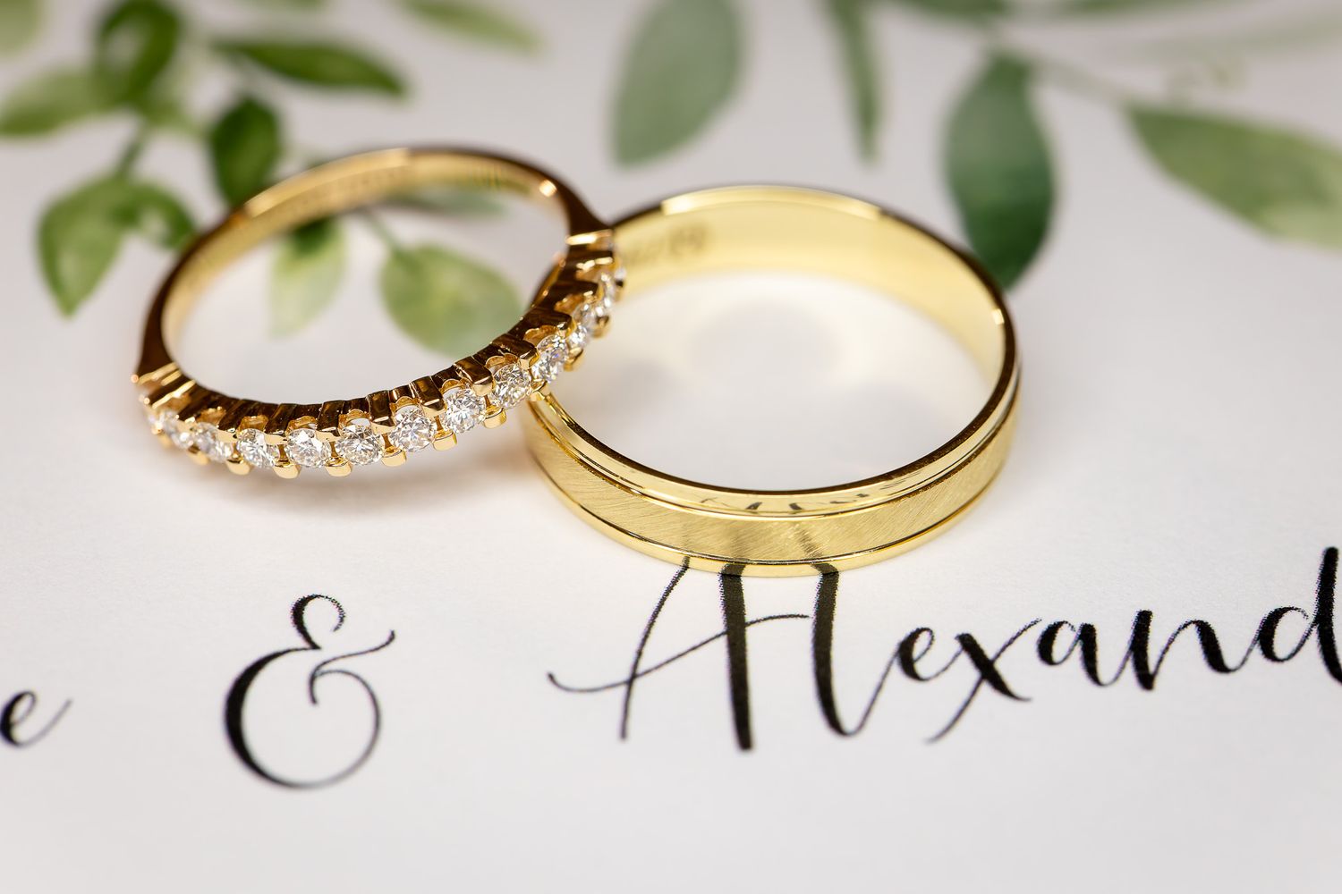 Gold wedding rings and elegant calligraphy on white paper with delicate details.