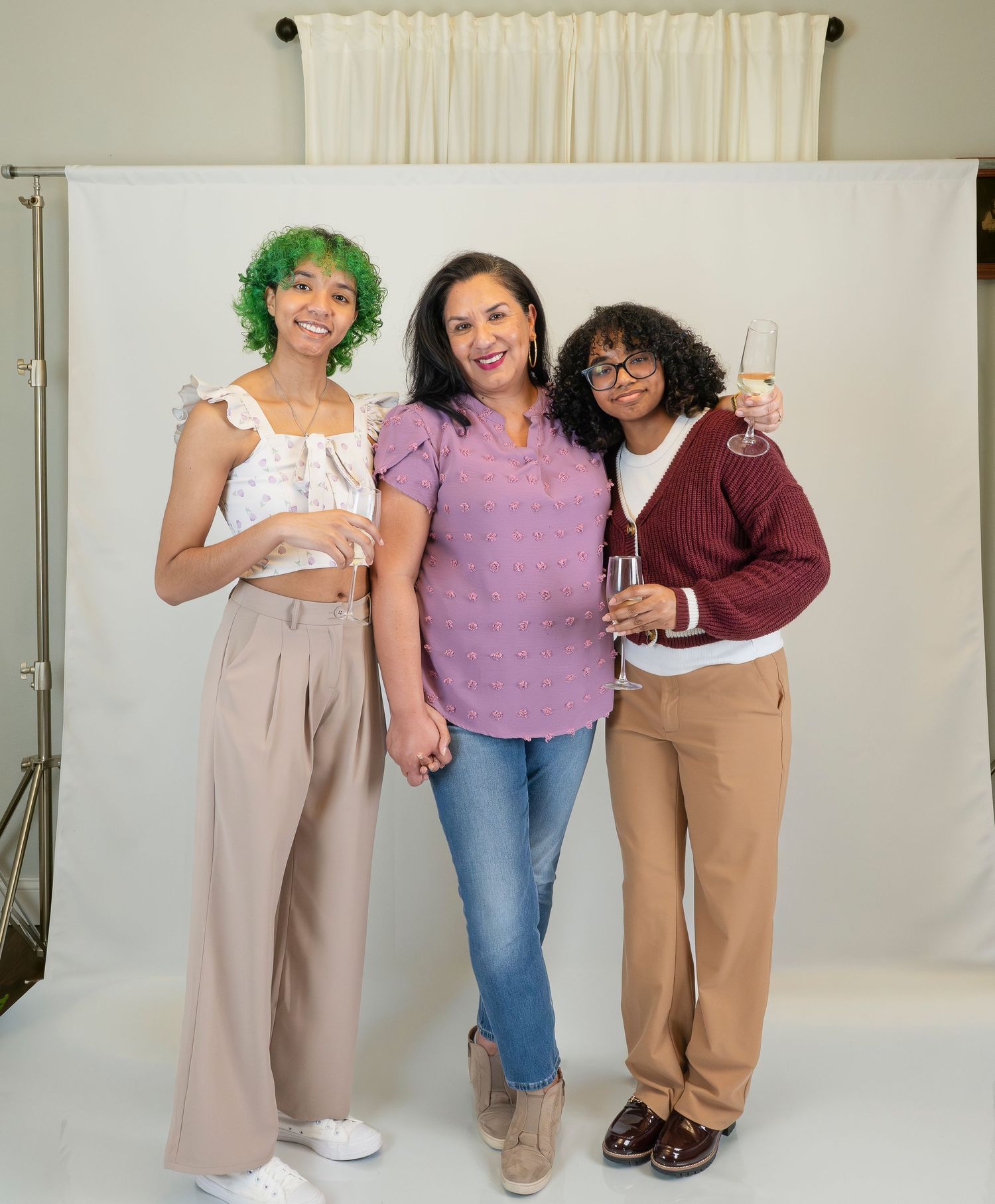 Five women posing together in a photo studio, smiling and holding champagne glasses for a celebration.