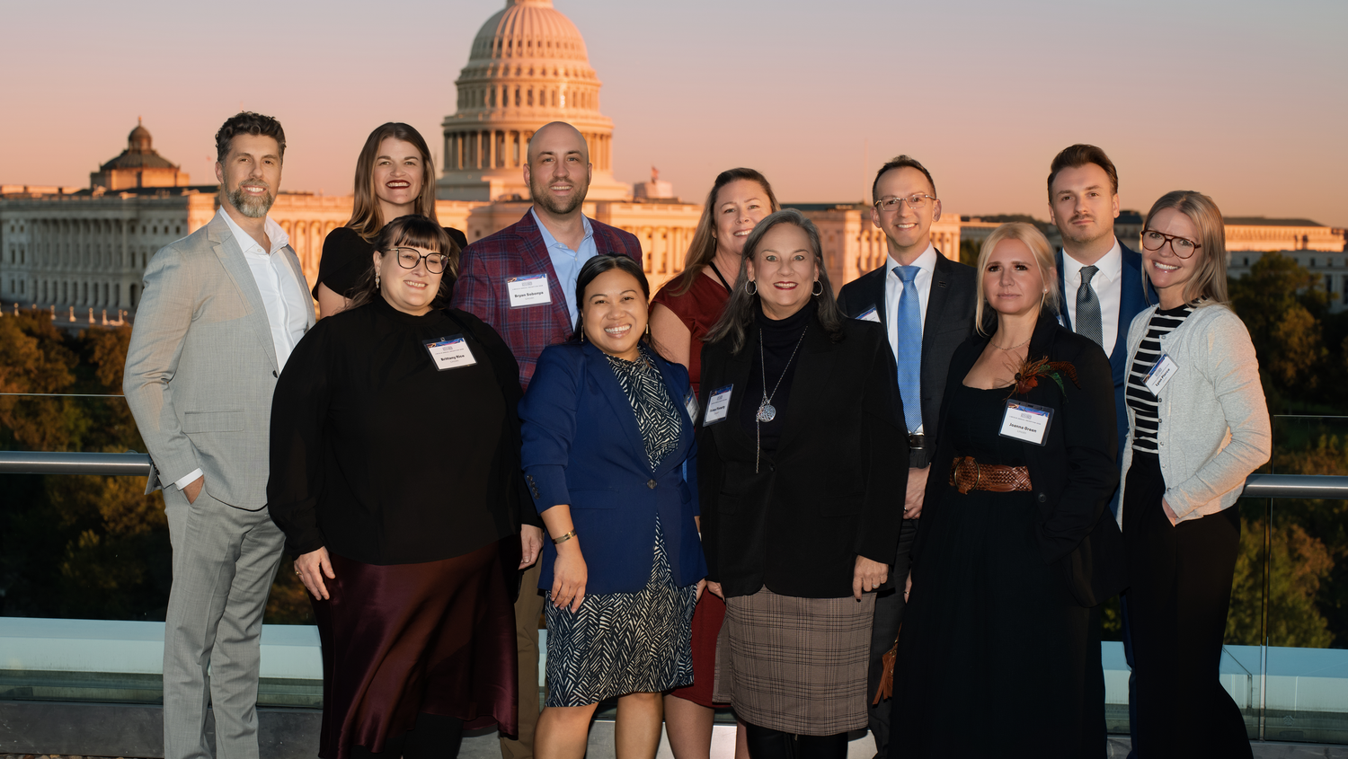 Guests pose on the 101 Constitution rooftop with the U.S. Capitol behind them at sunset.