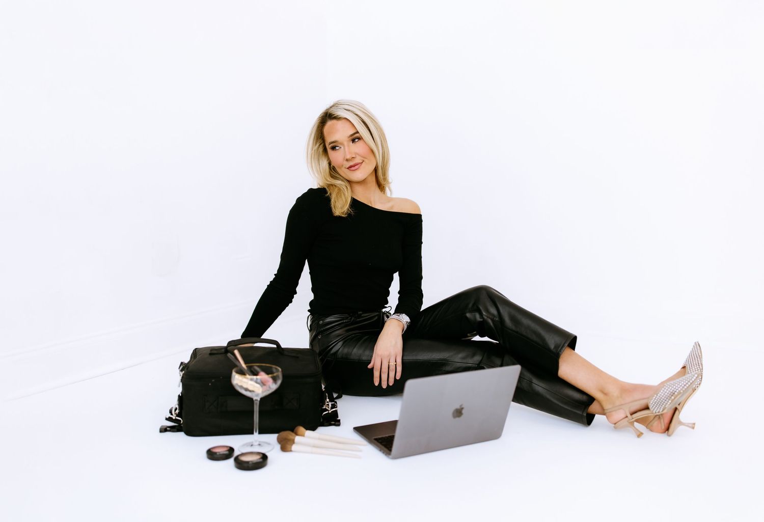 Professional reclining on floor with laptop, coffee and accessories against white background in studio setting.