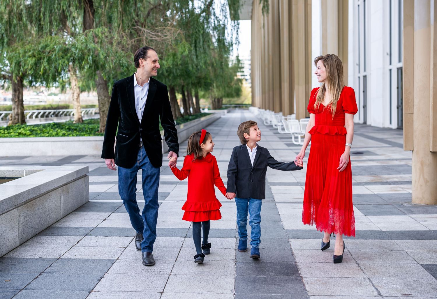 Family posing in front of The Kennedy Center in Washington, DC, with elegant architecture and the Potomac River in the b
