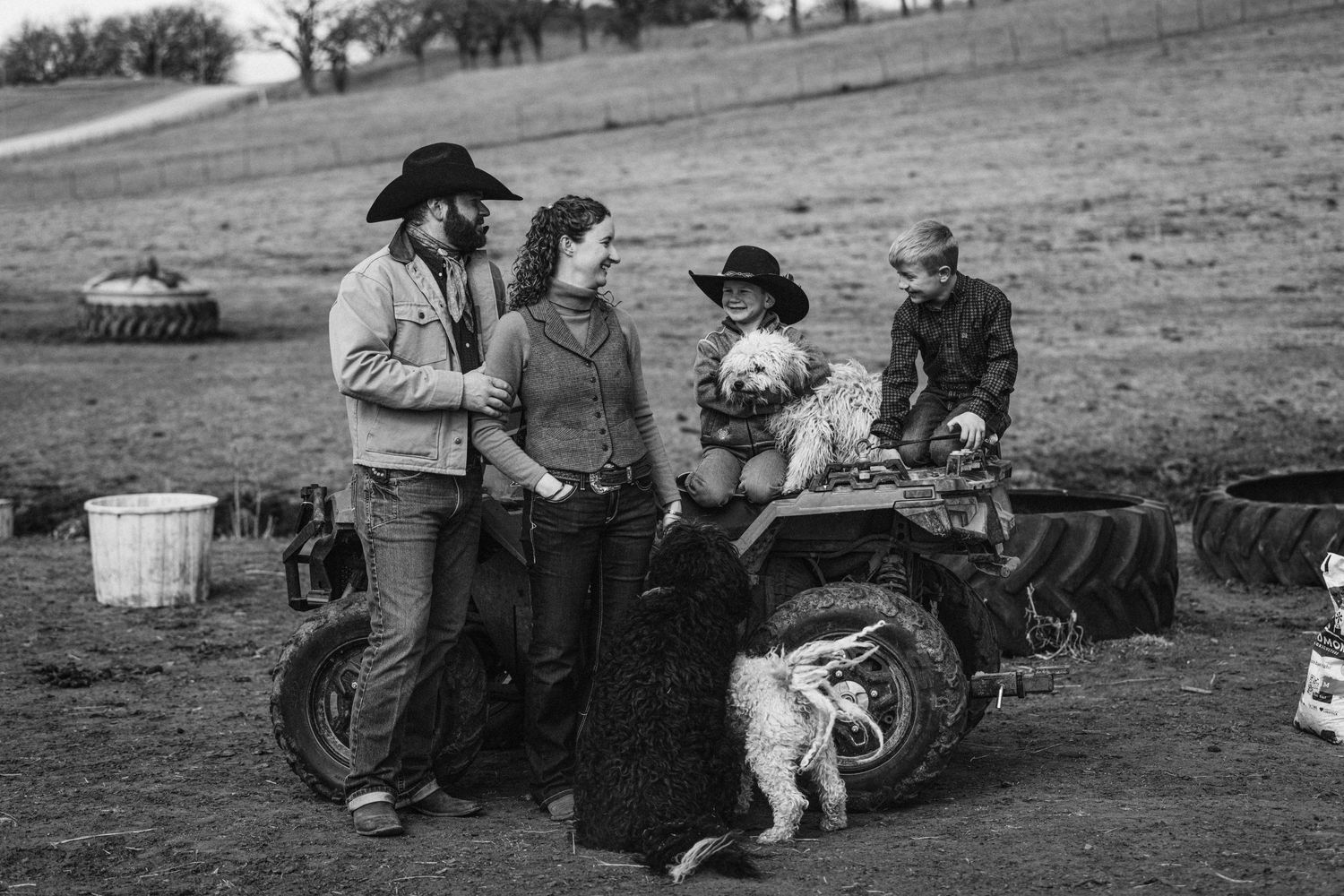 Group gathered around ATV on hillside with ranch dog.