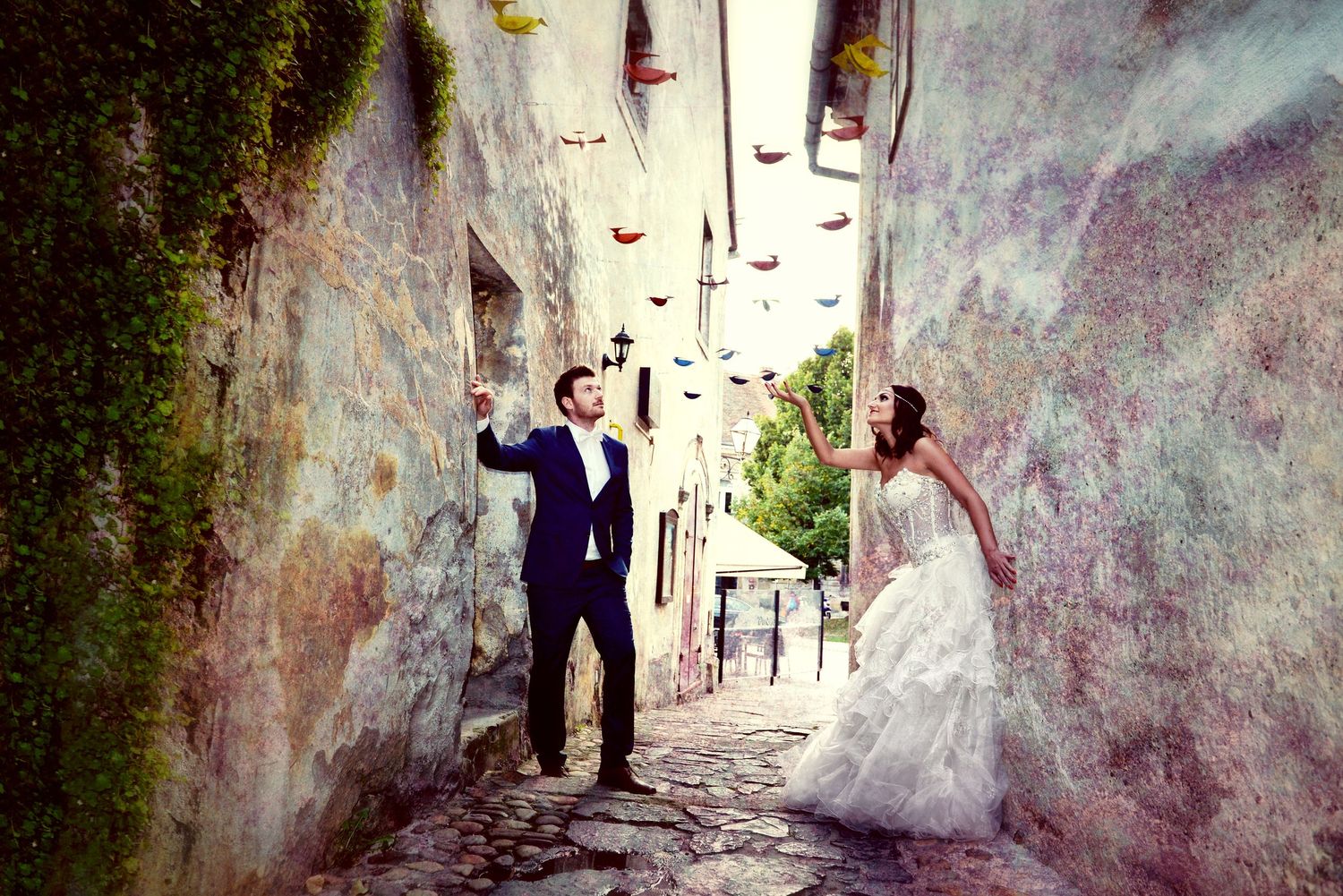 A bride and groom celebrate in a romantic narrow cobblestone alley with stone walls in European village.