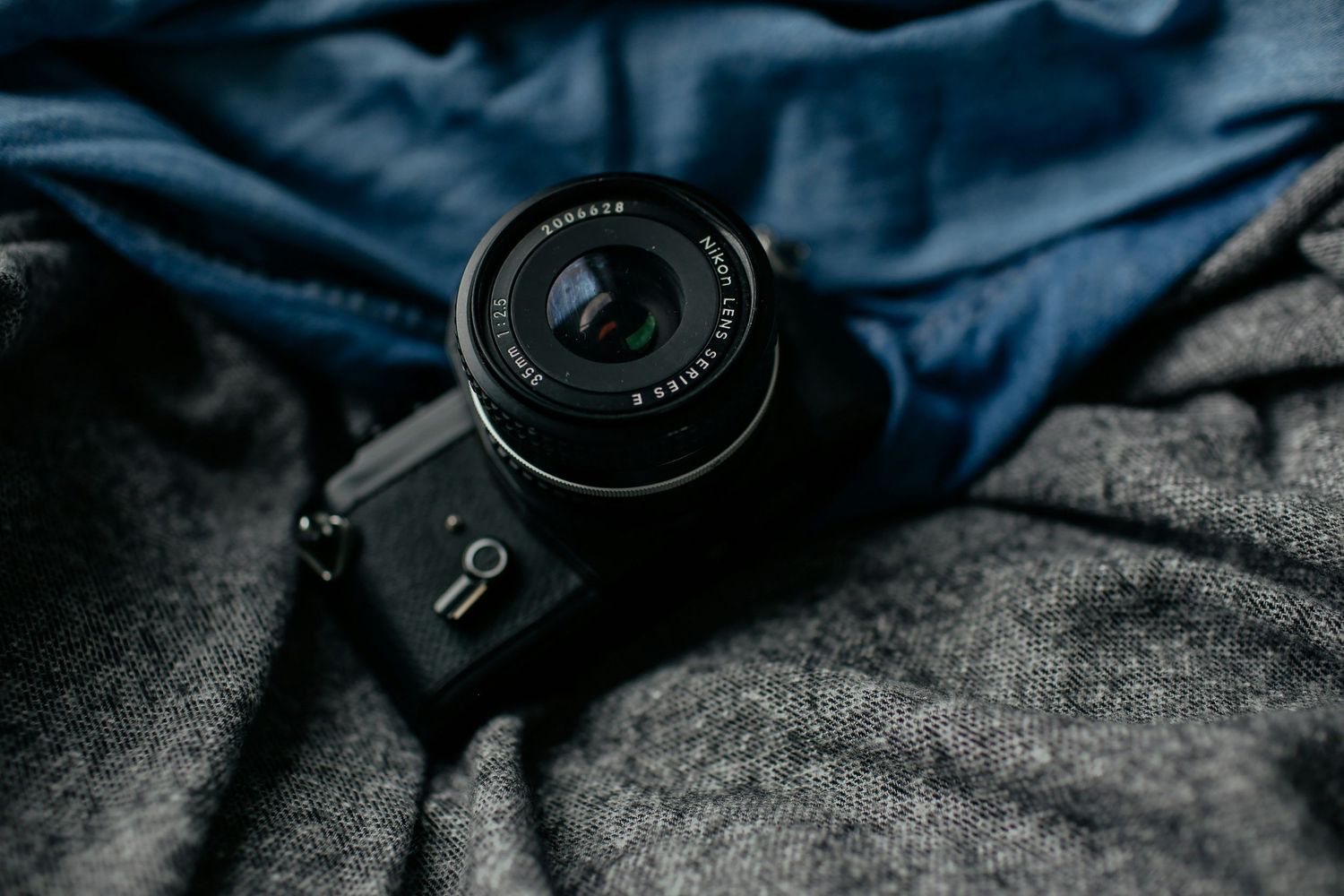 Black mirrorless camera with wide-angle lens resting on gray and blue fabric.