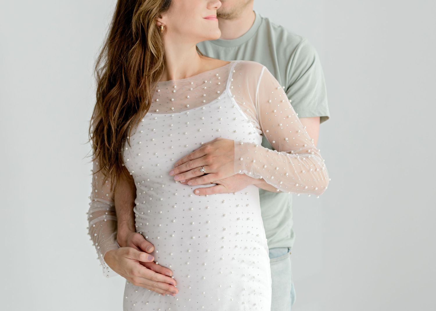 husband and wife cradling baby bump as they look at each other in Austin, TX