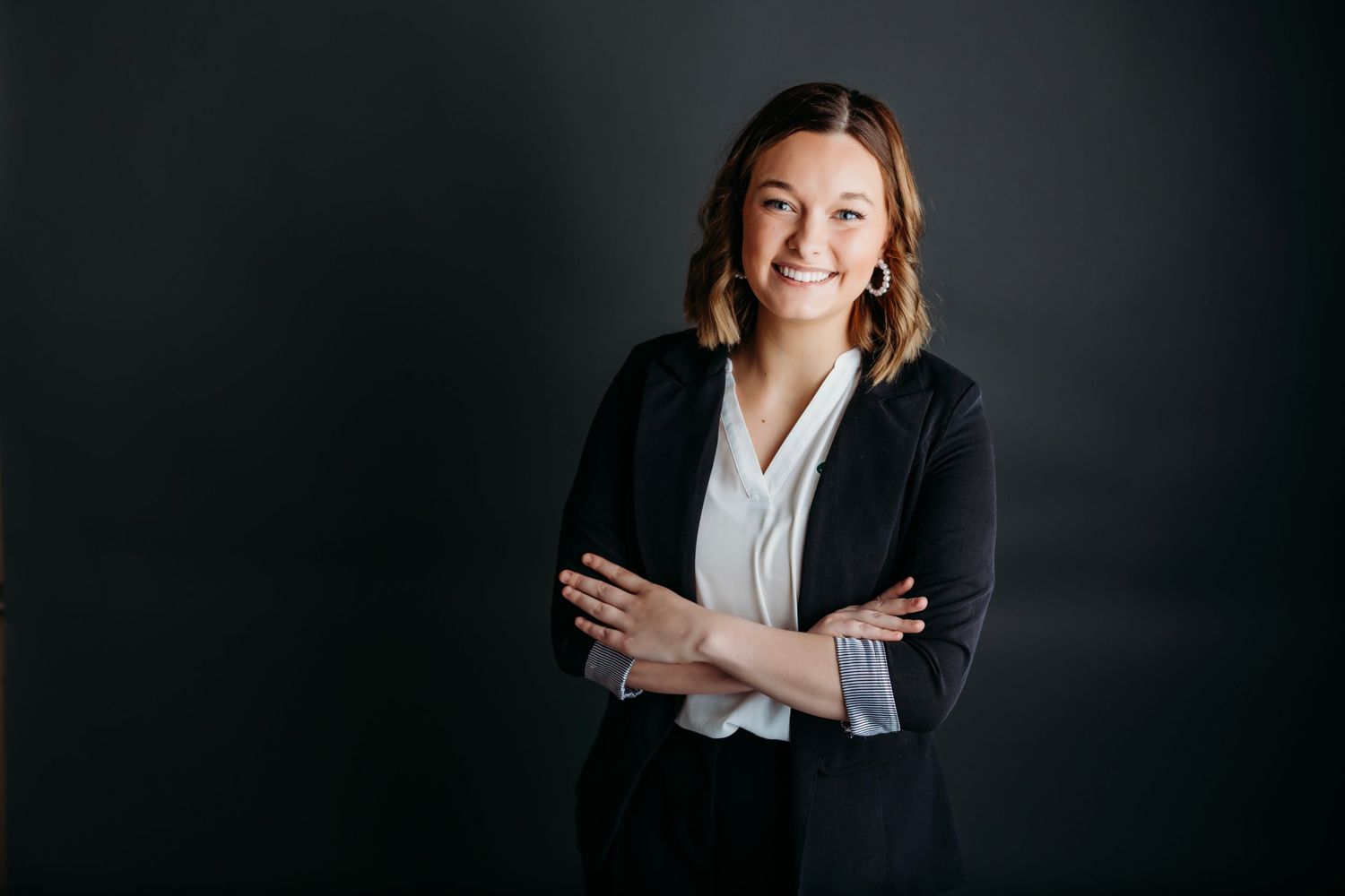 Professional headshot against dark background wearing gray suit and striped tie.