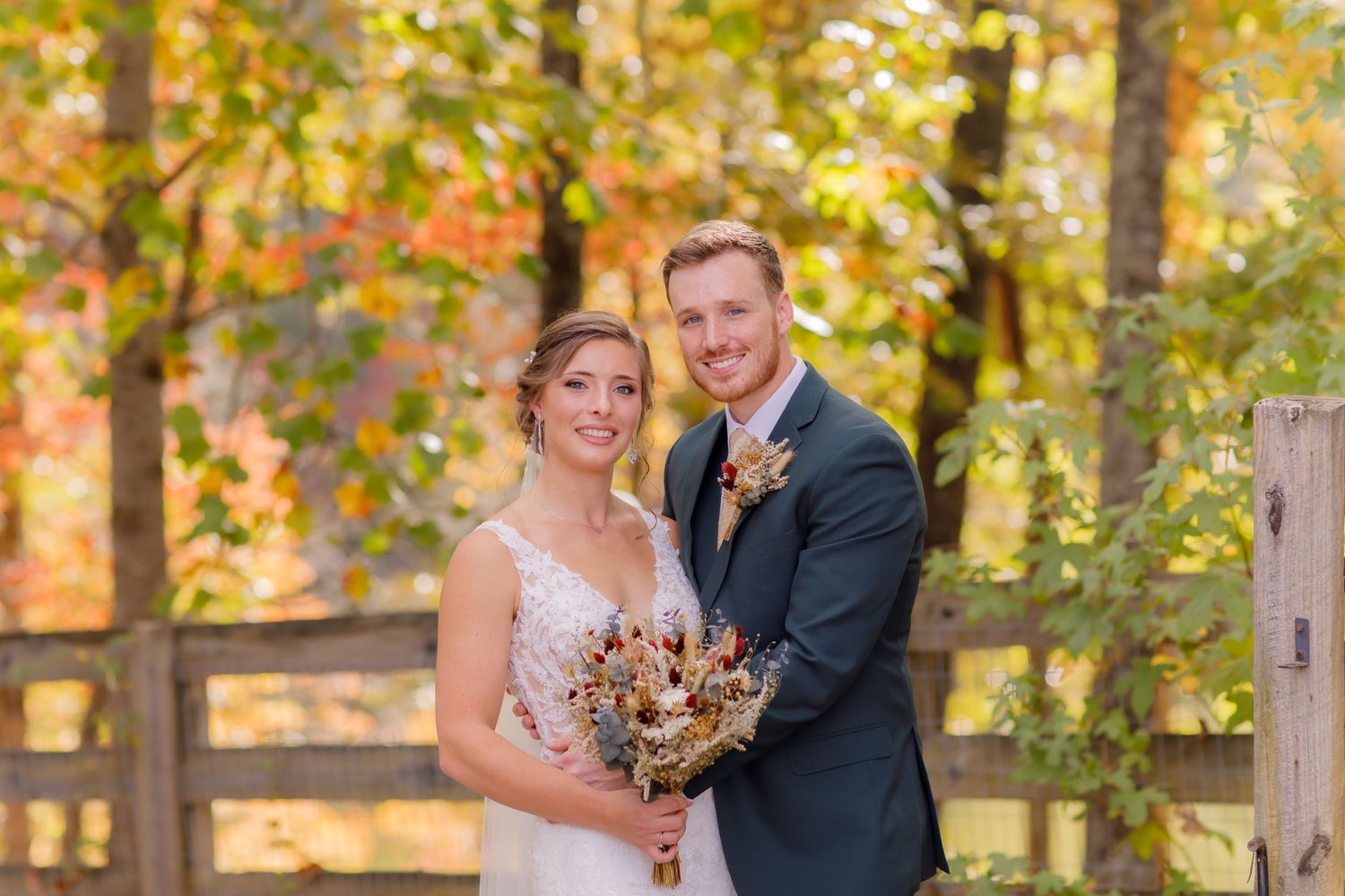 Autumn wedding portrait with fall foliage creating colorful natural backdrop.