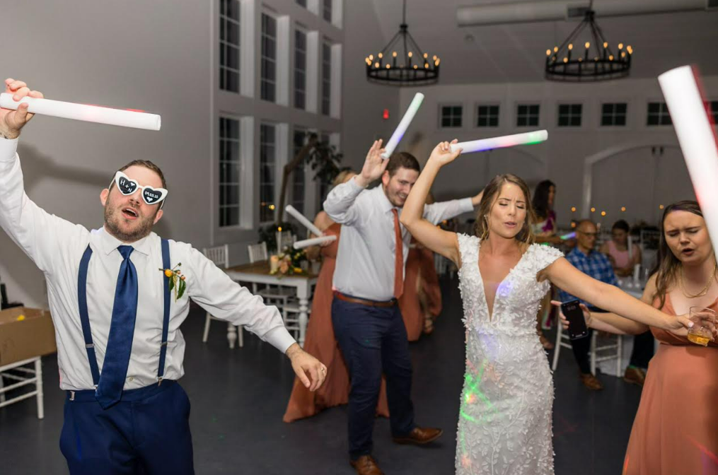 Bride and groom dancing with glow sticks at lively wedding reception party in elegant white venue | Sydney Allen Photography