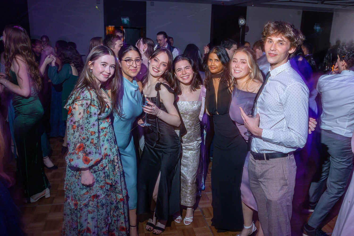 People dancing and socializing at a crowded party or nightclub with dim lighting and festive atmosphere.