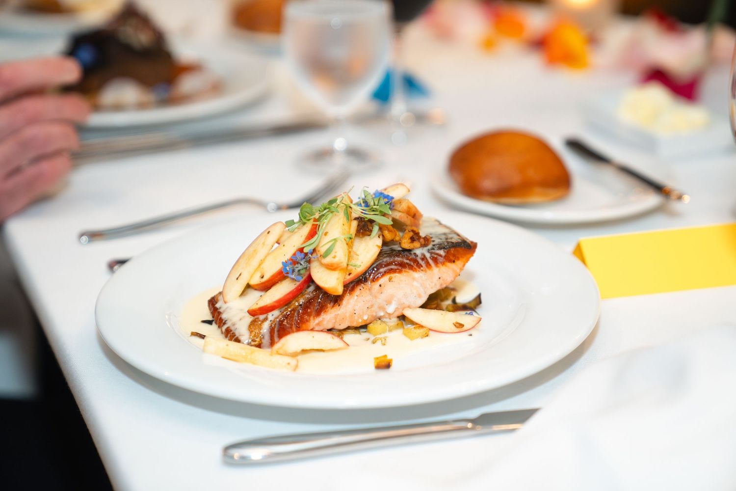 Elegant plated fish dish with crispy skin, sautéed vegetables, and garnish served on a white plate at a fine dining restaurant.