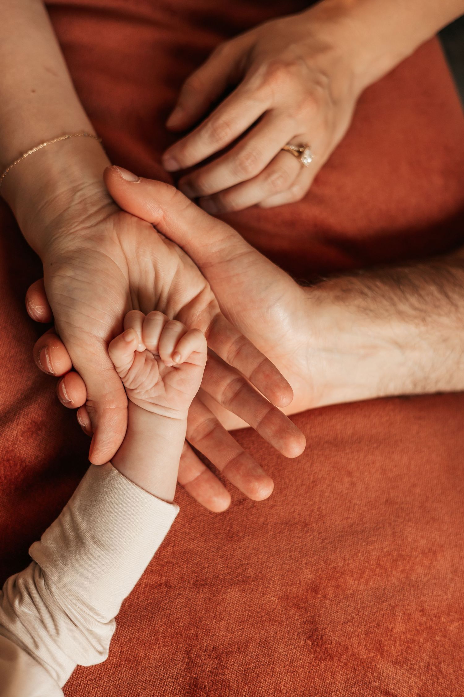A newborn baby's tiny hand resting on parents' hands, symbolizing family love  | Newborn Photographer in Broomfield Colorado