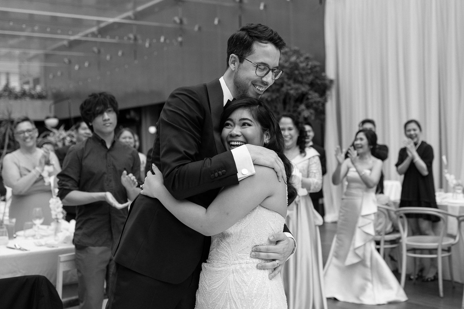 A bride and groom share an intimate moment outside an elegant stone building featuring ornate architecture.