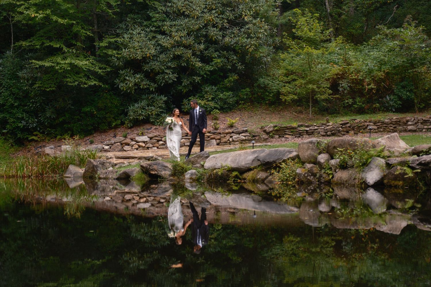 Couple Walking along waterfall at Flat Mountain Farm Highlands NC wedding venue