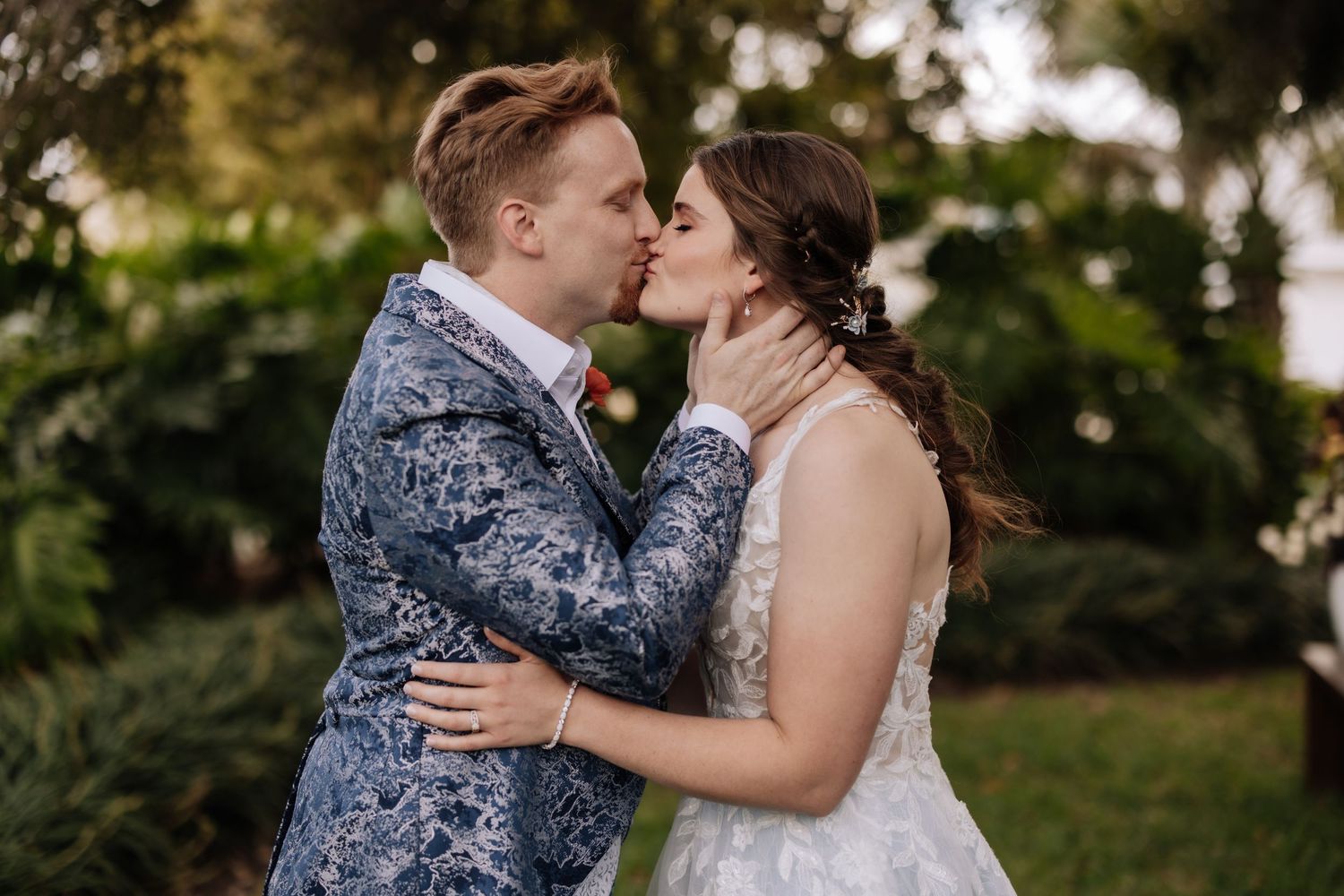 A couple shares an emotional moment during an outdoor wedding ceremony in a lush garden setting.