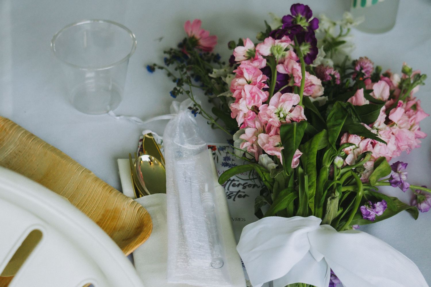A collection of pink orchids and white glass vases arranged on a wooden surface with natural light.