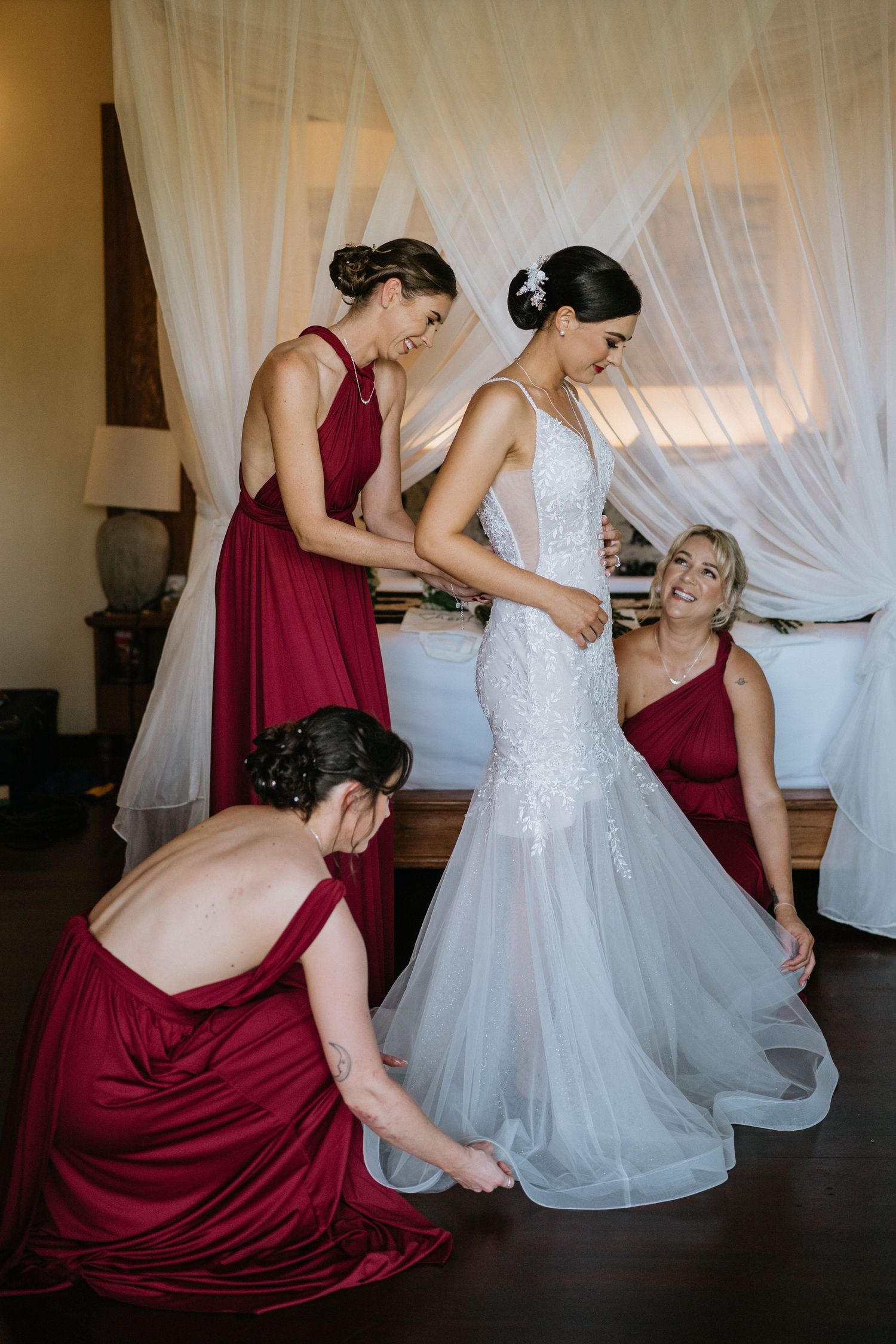 Wedding party poses outdoors with bridesmaids in red dresses.