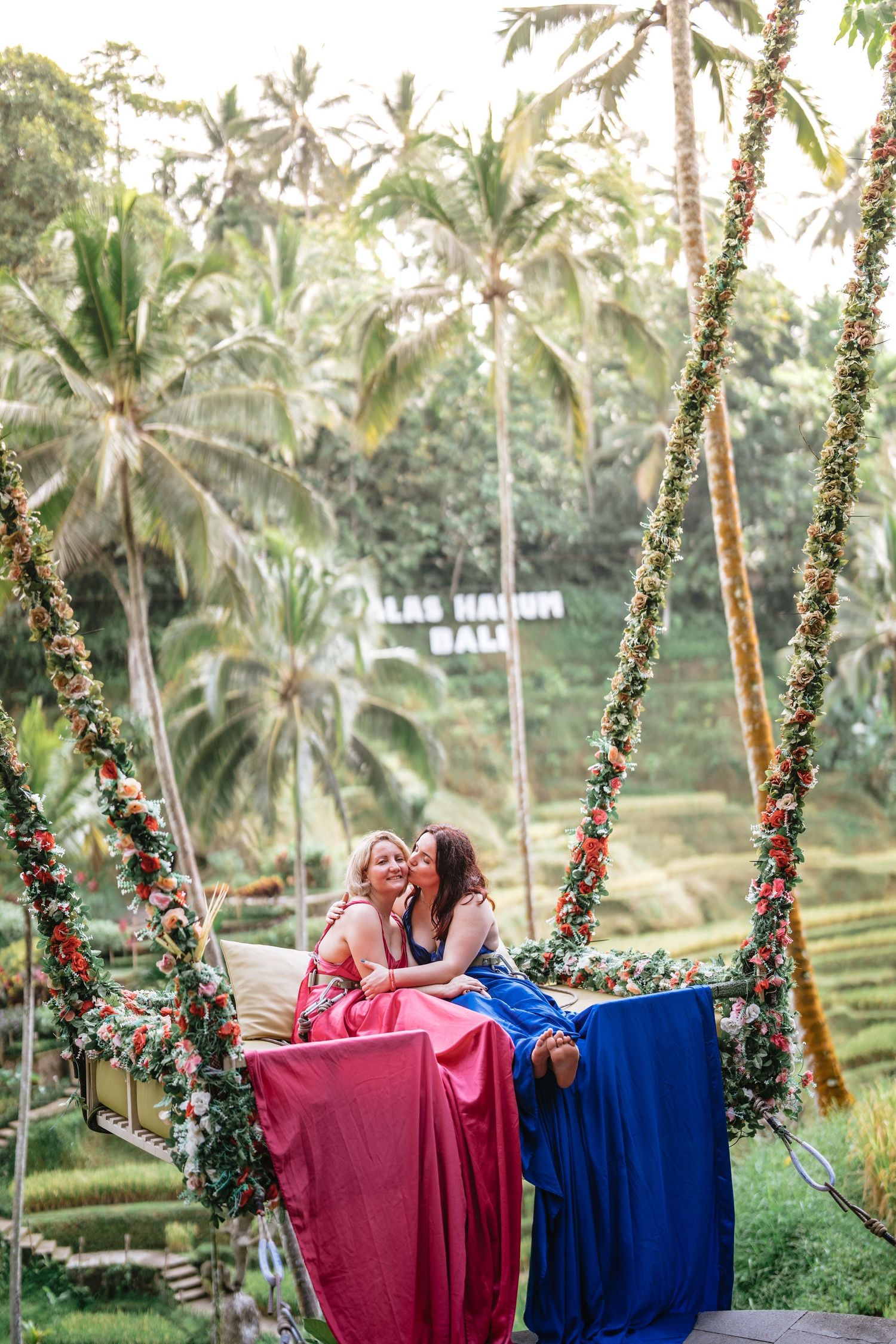 Couple walking along a green garden pathway surrounded by tropical plants.