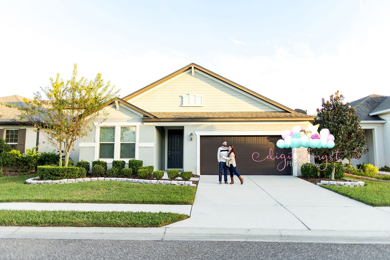 Panoramic view of suburban homes with well-maintained lawns and driveways on a sunny day.