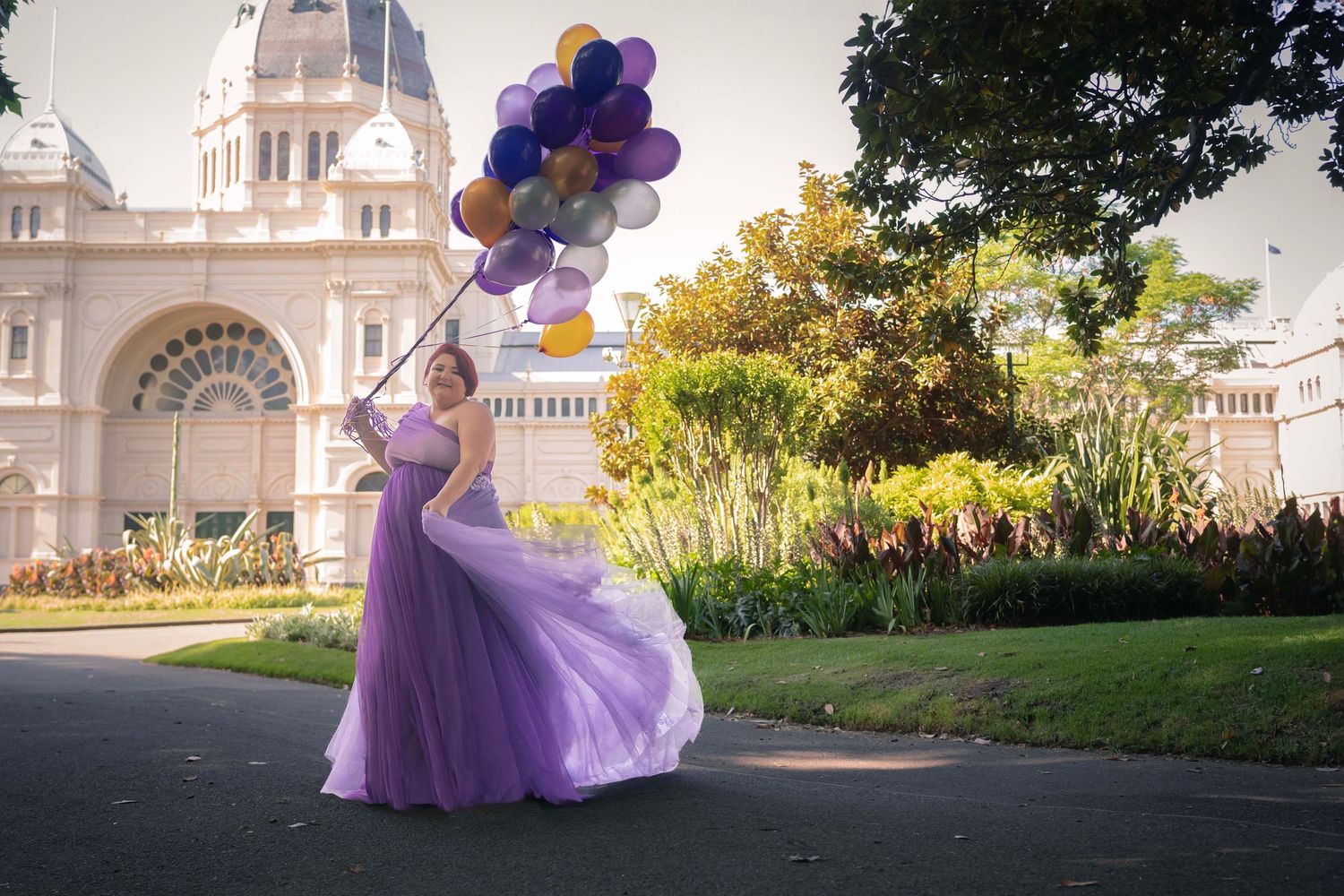 Purple balloons float above an elegant garden setting with a grand white building in the background.