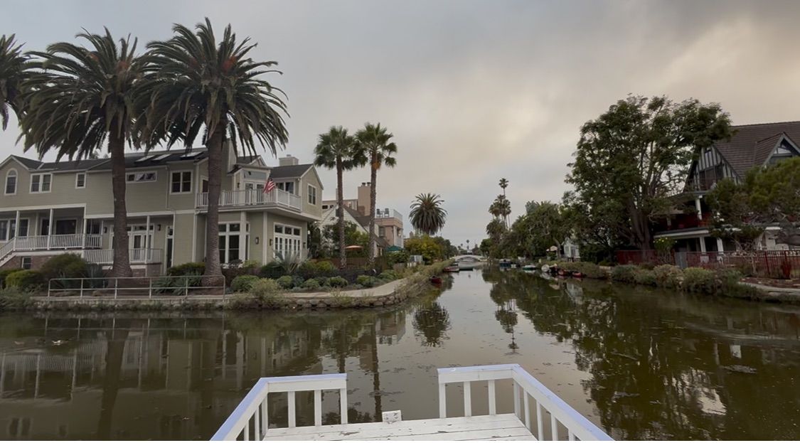 Storm surge flooding surrounds coastal homes and boats along a waterfront neighborhood during severe weather.