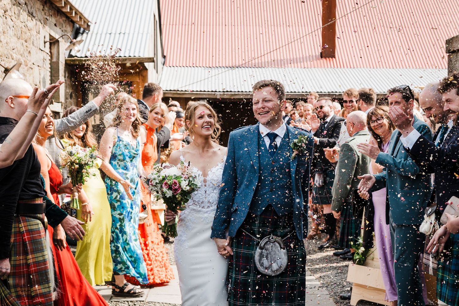 Wedding photo of bride and groom walking though a confetti shower thrown by guests at the Free Company Balerno near Edinburgh