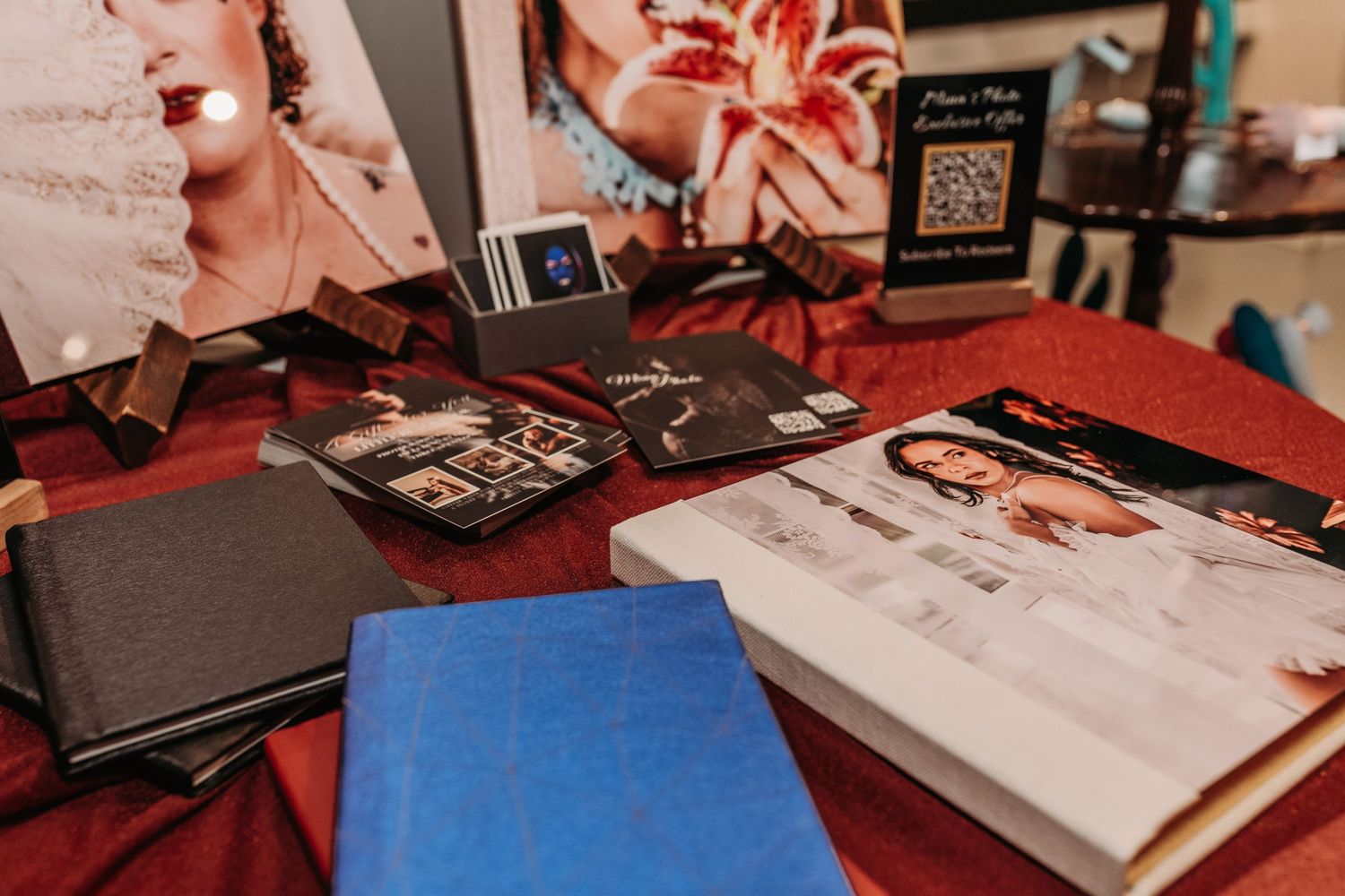Various photo albums and books scattered on a red table surface with a QR code visible in the background.