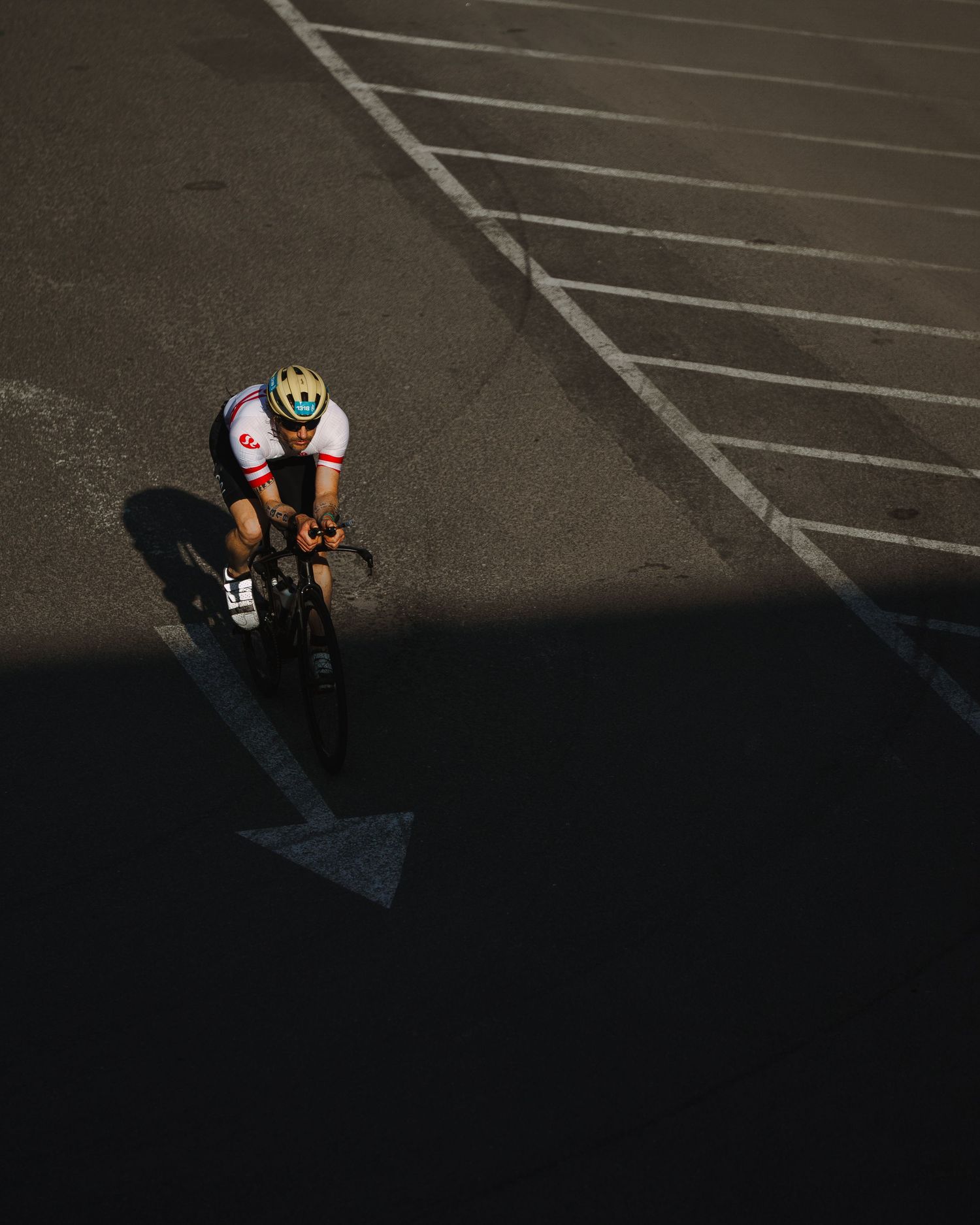 Low angle shot of cyclists' legs cycling on an asphalt street with shadows cast from bright sunlight.