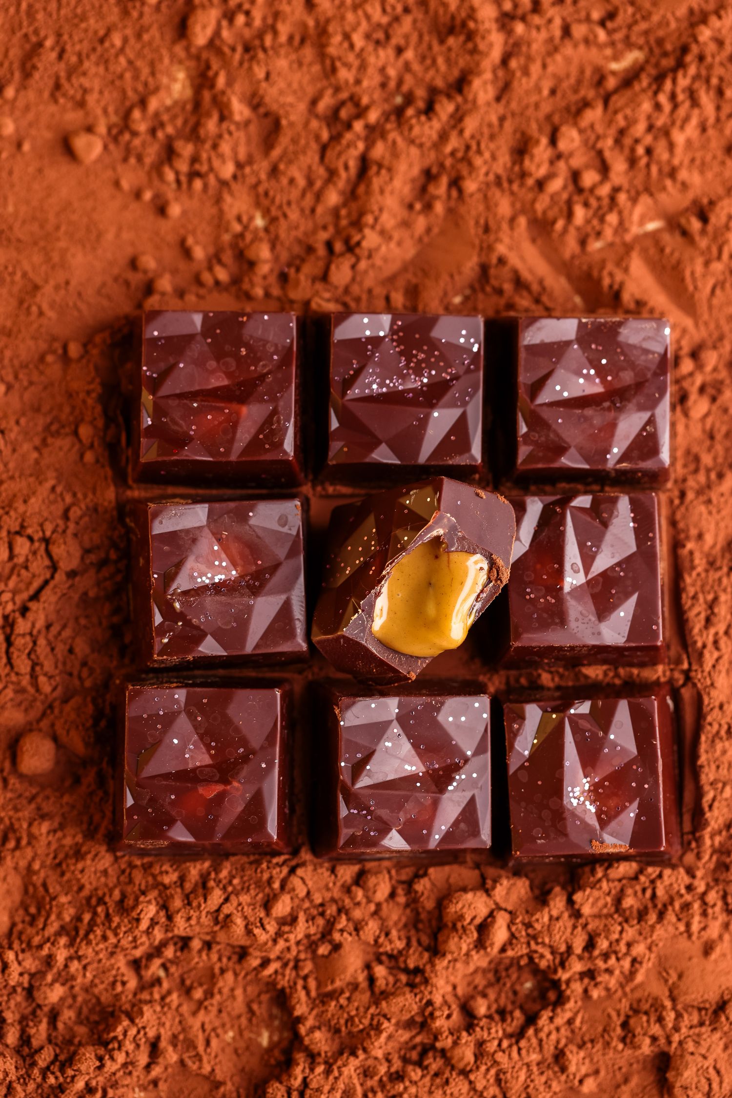 Geometric chocolate bar segments dusted with cocoa powder featuring a caramel center.