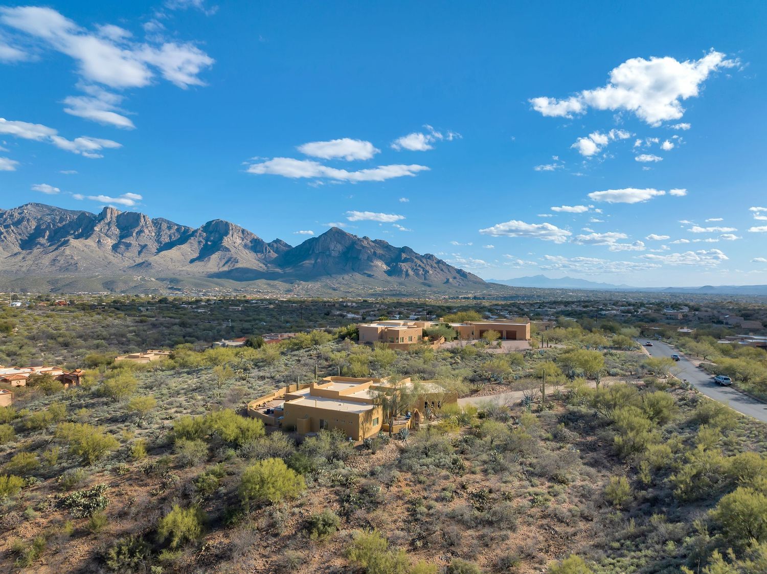 Aerial view of desert mountains and valleys with scattered buildings under bright blue skies.