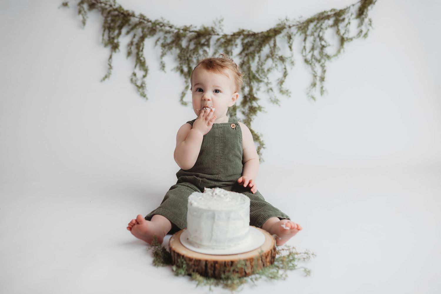A small baby with fair skin and light hair gazes upward with an innocent expression in a white setting.