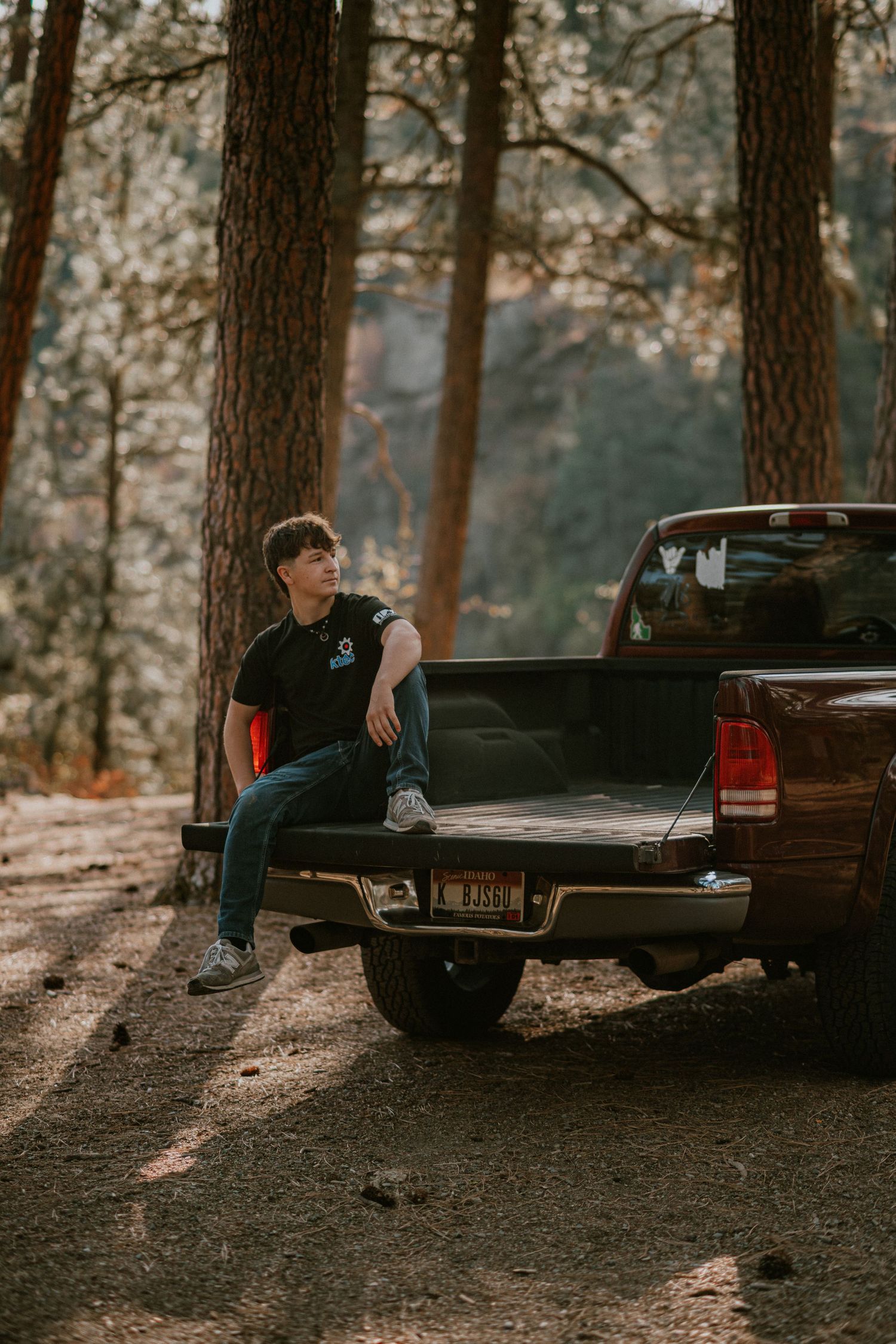 A moody photoshoot in the woods by a pickup truck bed at sunset showcasing four different dramatic poses.